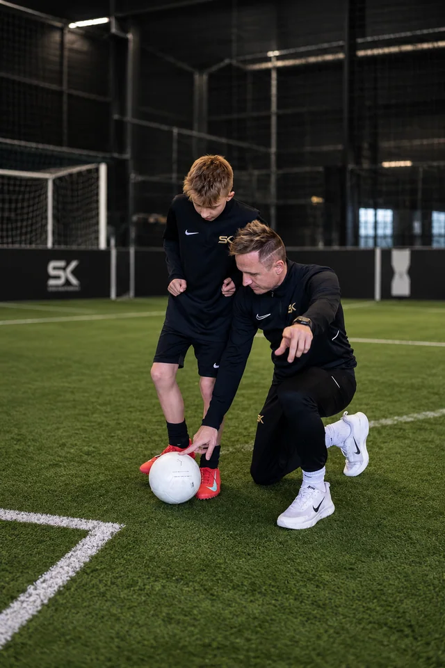 Stefan Kehrer erklärt einem Jungen eine Fußballtechnik im individuellen Training auf Kunstrasen